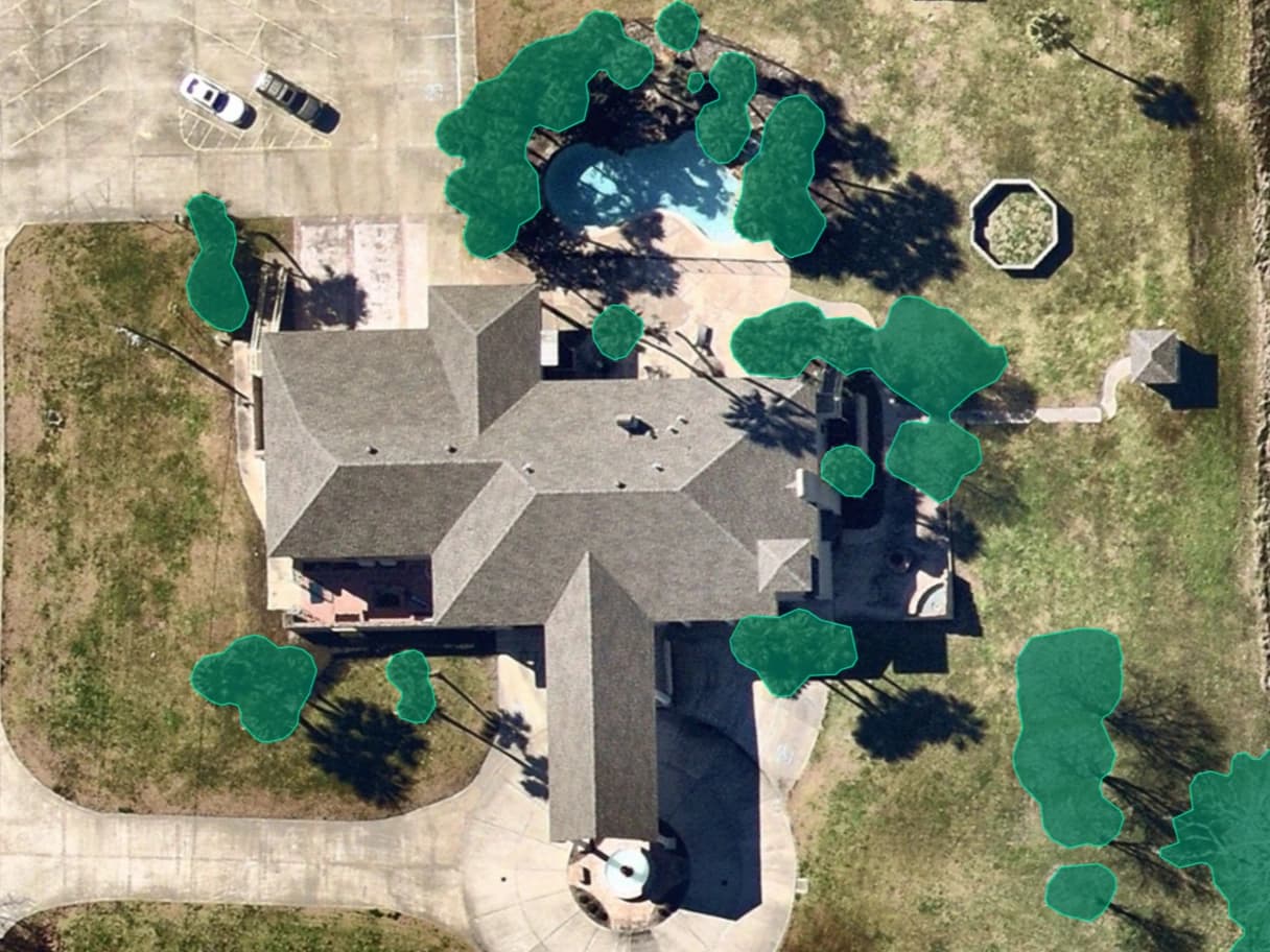 Aerial property image with green overlays highlighting vegetation around a building